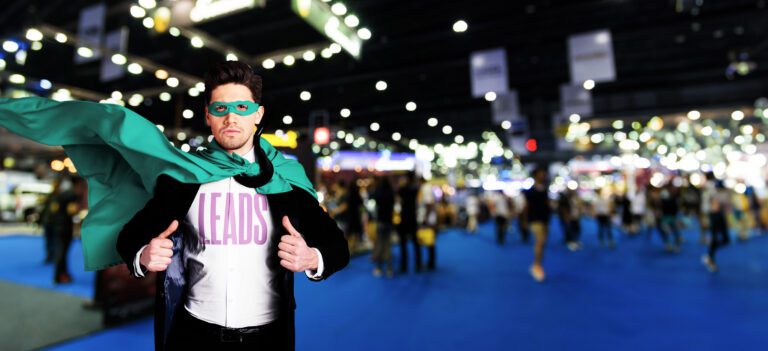 a man wearing a shirt that says "leads" and a green super hero cape at a convention