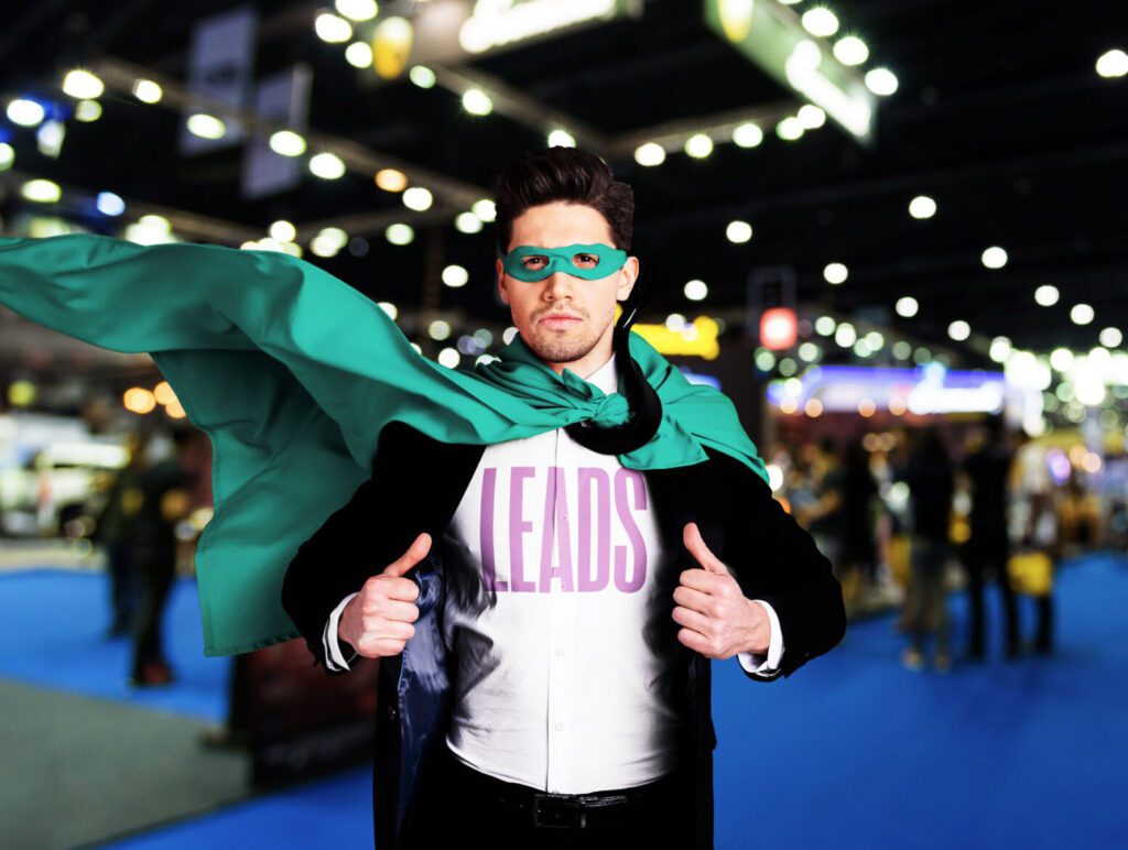 a man wearing a shirt that says "leads" and a green super hero cape at a convention