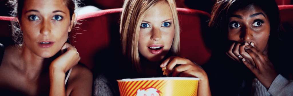 three women at the movies eating popcorn