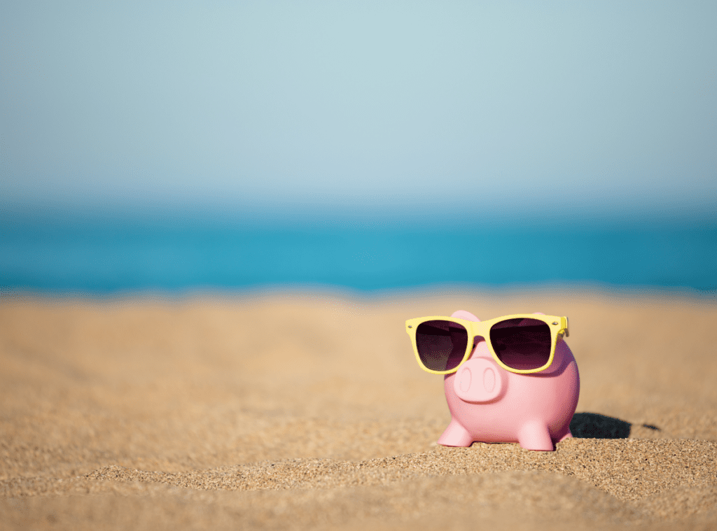 piggy bank with sunglasses on on the beach