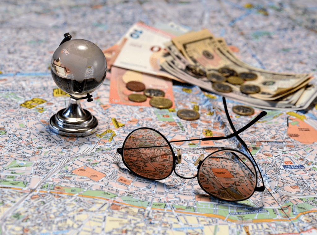 sunglasses and money on top of a map to indicate travel