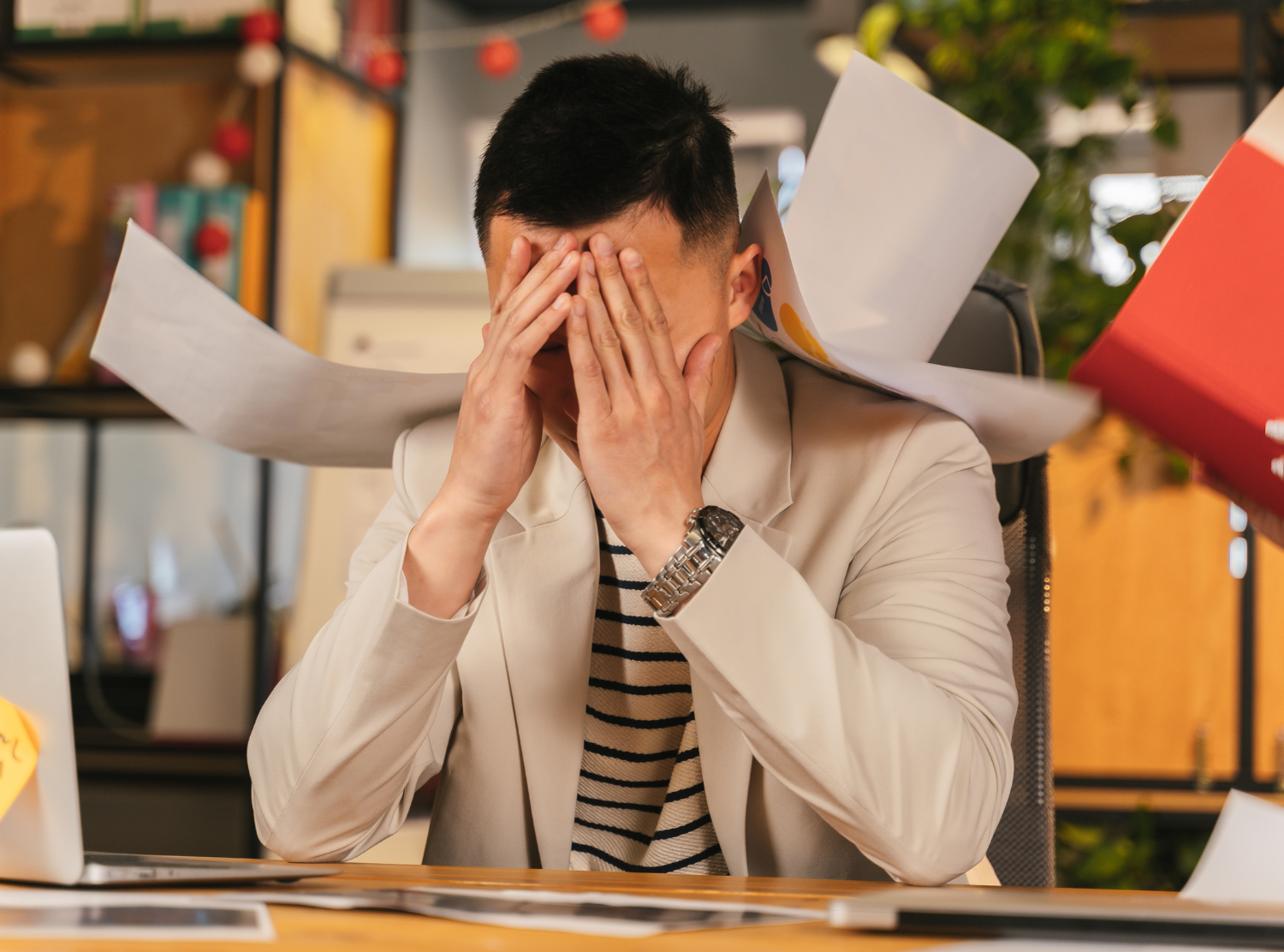 stressed man at desk with papers flying around him