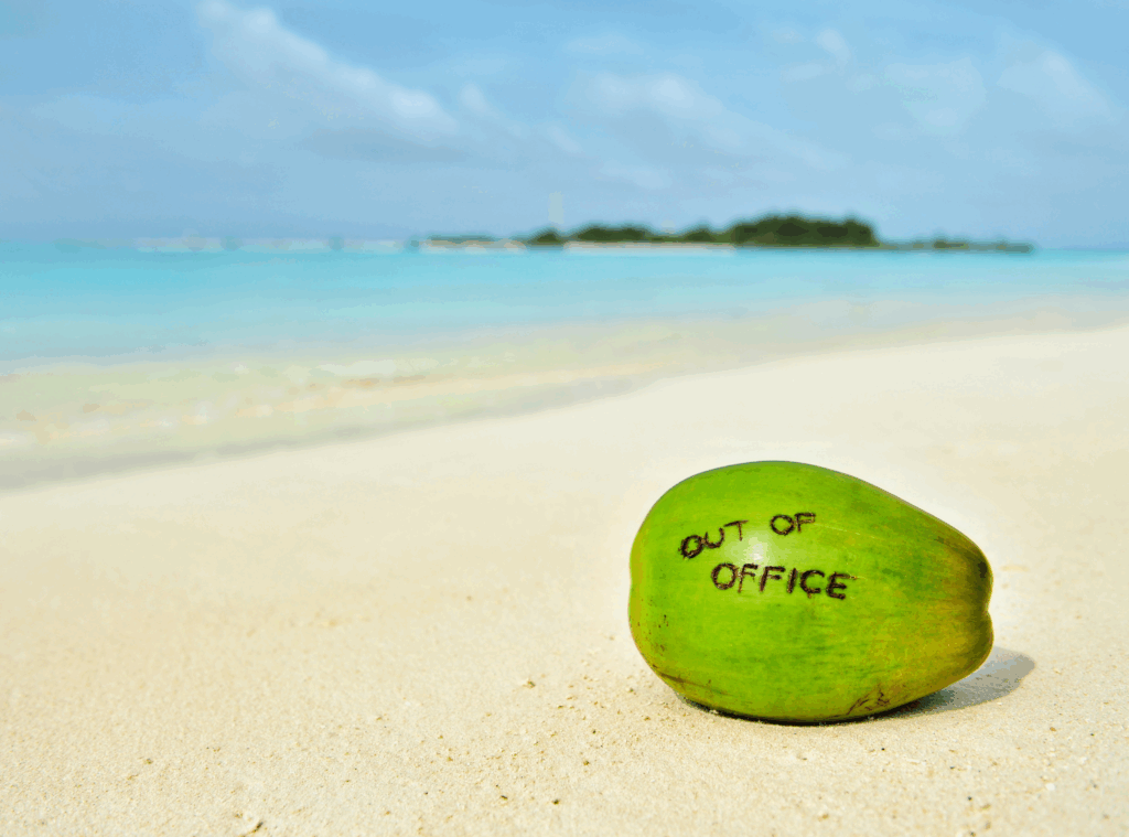 coconut on beach with "out of office" written on it