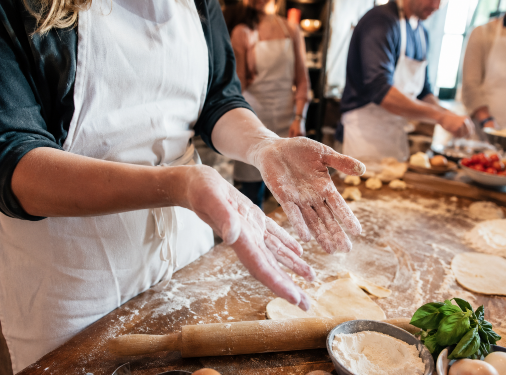 Flour-covered hands at a travel cooking class show a visitor learning a new skill through a tourism experience