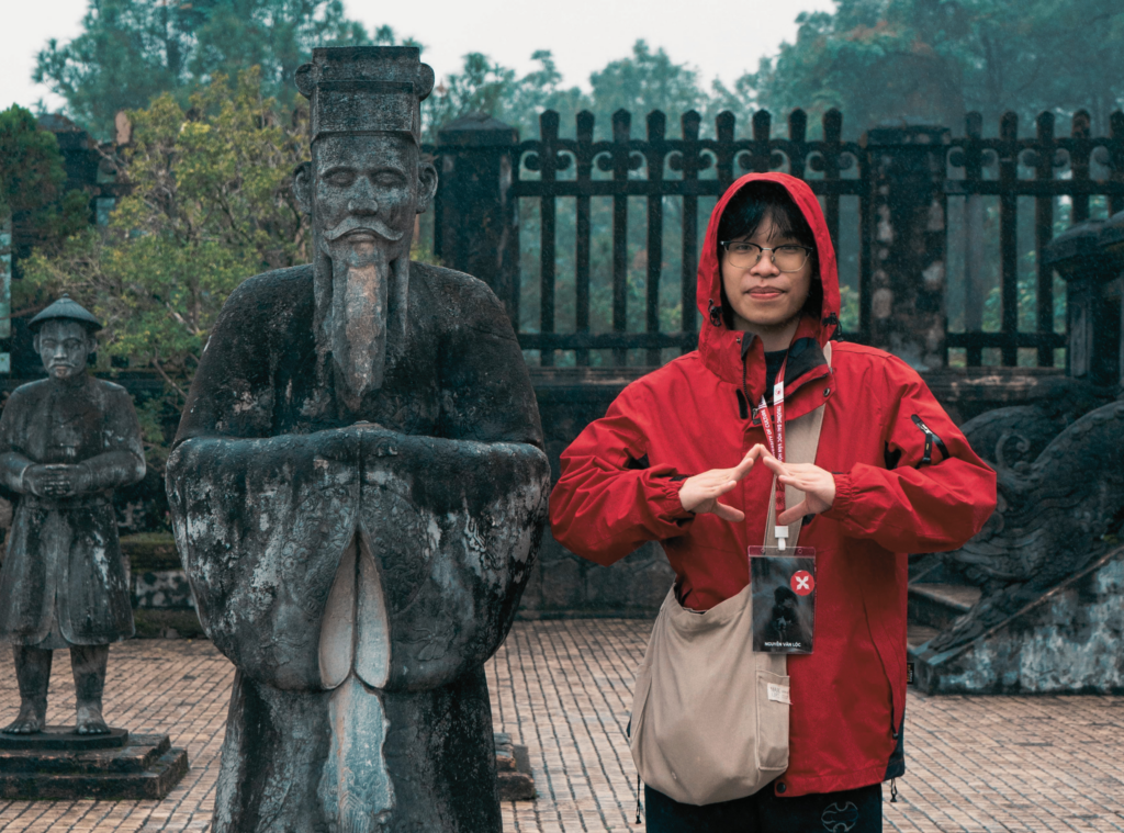 Traveler in a red raincoat stands near a fountain and historic gate, showing how the visitor becomes the main character